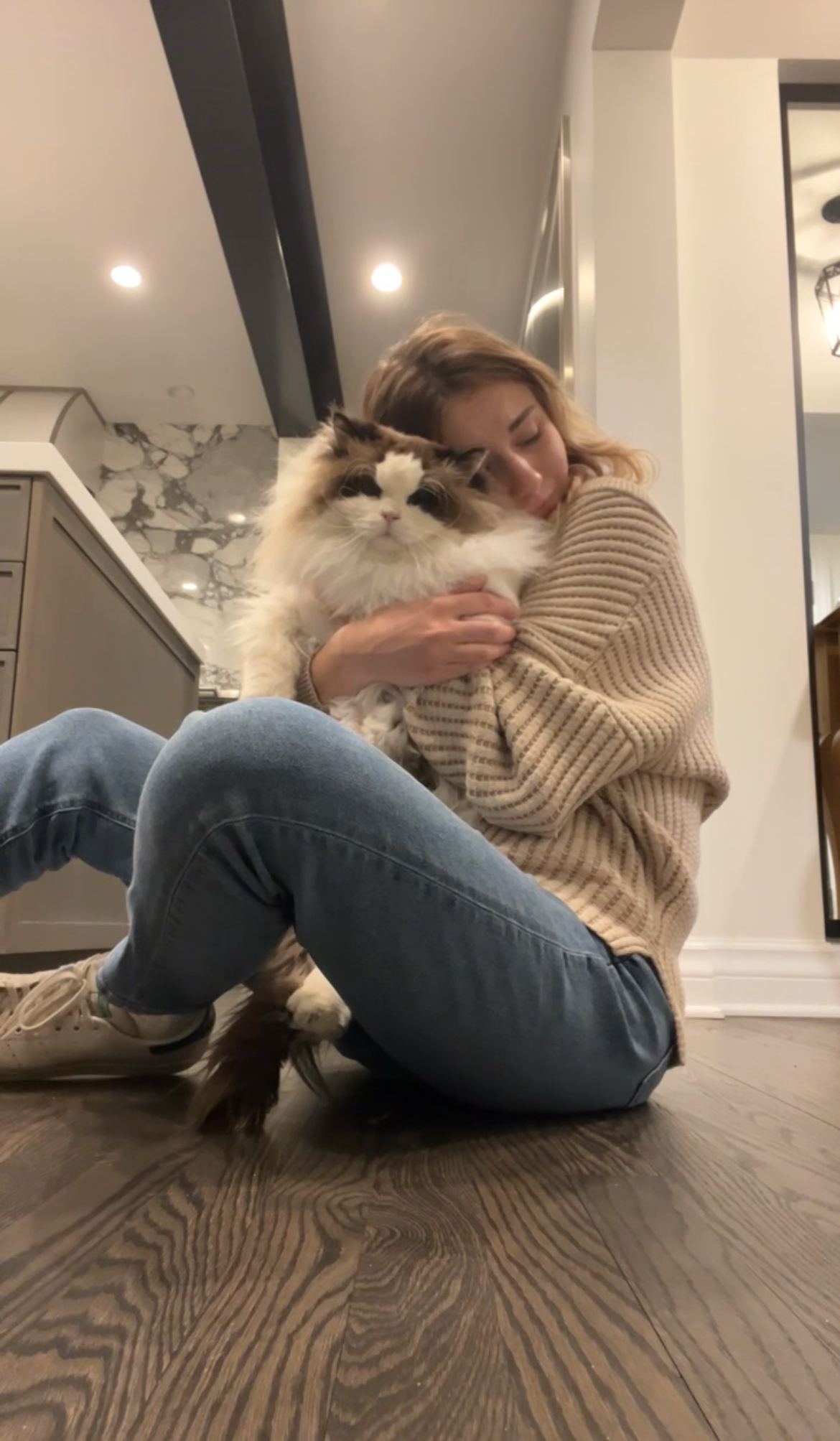 Samantha cuddling with a beautiful fluffy cat on the kitchen floor